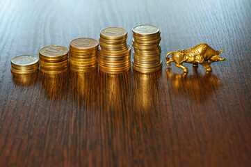 A metal bull and a pile of coins on the table.