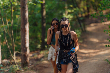 Sisters hiking through beautiful woods while wearing a backpack and enjoying nature. Female bonding.