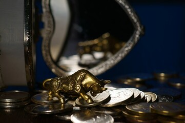 Bull and a stack of coins close-up on the table. In the background is a jewelry box.
