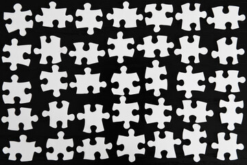 Naklejka premium Grid rows of white jigsaw puzzle pieces on a black table