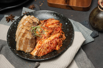 Korean Boiled Pork with preparing cabbage kimchi in black dish. Korean traditional cuisine. Fermented food.