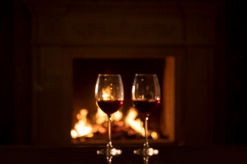two glasses of red wine - romantic dinner against the background of a burning fireplace  