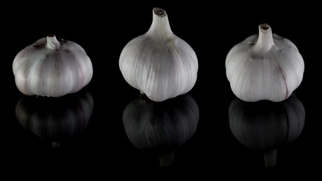 three heads of garlic at black background, demonstrating showcase