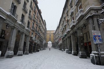 View of the access doors of the historic Plaza Mayor of Madrid covered with snow under a heavy snowfall.