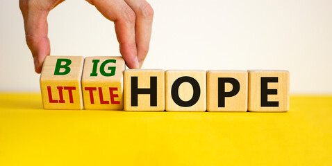 Little or big hope symbol. Hand turns wooden cubes and changes words 'little hope' to 'big hope'. Beautiful yellow table, white background, copy space. Business and hope concept.