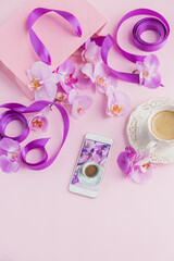 Pink home office workspace with phone and coffee cup. Social media flat lay with coffee, flowers and smartphone. Female floral workplace