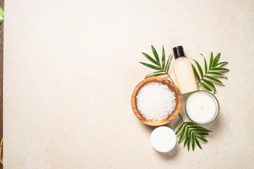Obraz na płótnie Canvas Spa background. Spa product composition with palm leaves, cosmetic and sea salt at stone table. Flat lay image.