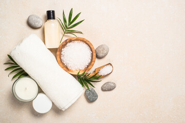 Naklejka na ściany i meble Spa background. Cosmetic product, towel and sea salt at stone table. Top view image.
