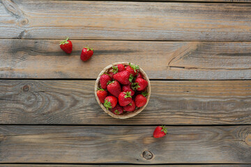 Heap of fresh strawberries in a basket on rustic wooden background. Healthy eating and diet food concept.