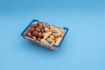 Grocery basket with peanuts and hazelnuts on a blue background