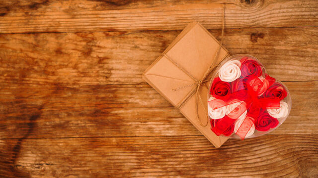 Letters in craft paper envelopes and a gift of roses on a wooden background