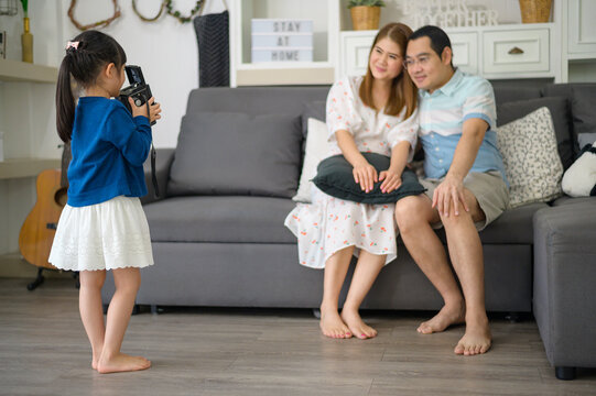 a cute Asian daughter holding camera is taking photos of her parents at home on weekends.