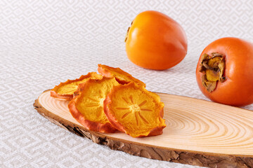 Dehydrated persimmon fruit slices and whole fresh tropical fruits.