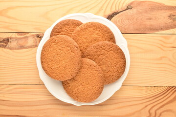 Several delicious round American cookies on a ceramic white plate, close-up, on a wooden table.