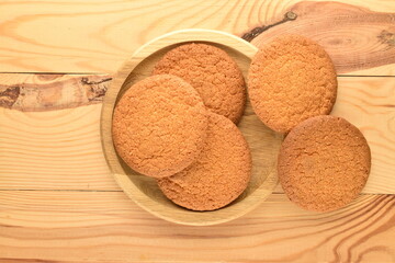 Several delicious round American cookies on a round wooden tray, close-up, on a wooden table.