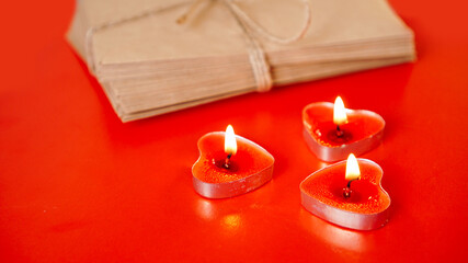 Kraft paper envelopes with red candles on a red background. Valentine day concept
