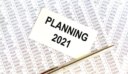 Obraz premium On the business card tectonics Planning 2021, next to the pen, the background are reports.