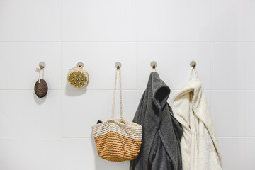 Two bathrobes, a basket and sustainable zero waste bathroom accessories on a white wall. Sustainable home, plastic free bathroom concept.