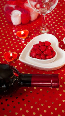 Valentines day. Bottle of vine, glasses, red roses, candles - red background. Love dinner concept - Vertical photo
