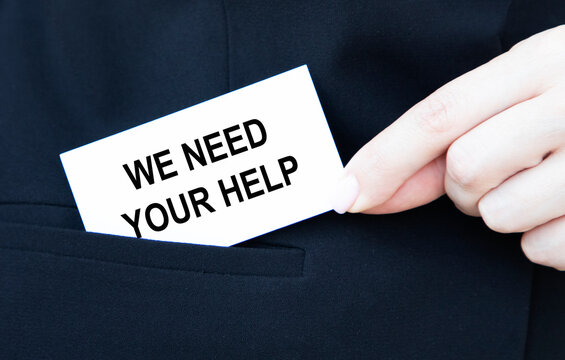 A businessman puts in his pocket a business card with we need YOUR HELP.