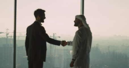 Collaboration people. Young successful businessman making agreement corporate business deal with Arabian entrepreneur standing by window. - Powered by Adobe