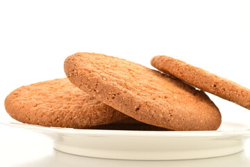 Several freshly baked round American cookies on a ceramic saucer, close-up, isolated on white.