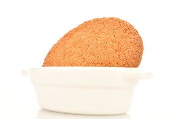 One freshly baked round American cookie in a ceramic white dish, close-up, isolated on white.