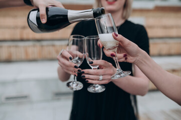 young girls pour champagne into glasses