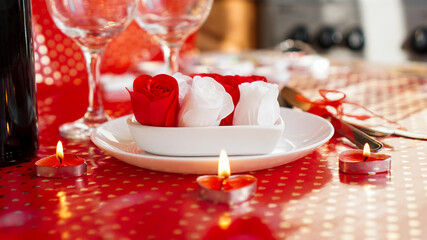 Valentines day. Bottle of vine, glasses, red roses, candles - red background. Love dinner concept