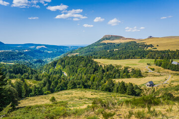 Fototapeta na wymiar the landscape between the small town of Chambon sur le Lac and Mont Dore, in Auvergne (France). Hills and meadows as far the eye can see