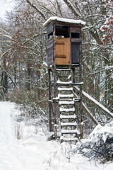 A deerhunter's perch with snow-covered ladder in a forested area in Bavaria during winter