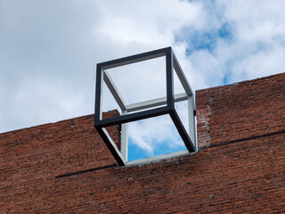 A frame cube installed on the roof of a brick building. Modern urban design element.