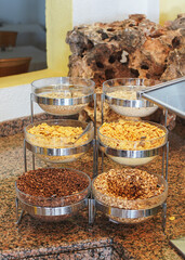 Corn, cereals and rice flakes in glass bowls displayed at restaurant breakfast buffet table