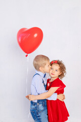 valentine's day kids. Boy kisses girl five years old holding red ball heart