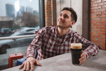 Fototapeta na wymiar Cheerful young man smiling, watching tv at beer pub, copy space