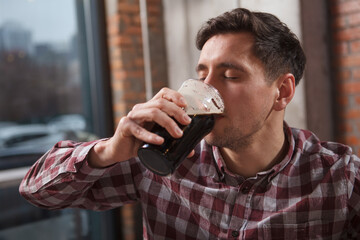 Fototapeta na wymiar Close up of a man sipping tasty craft beer with his eyes closed in pleasure