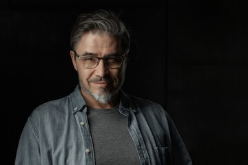 Portrait of casual older man with beard against dark background.
