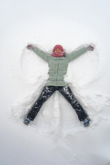 The woman lies down in the snow. Snow angel, top view