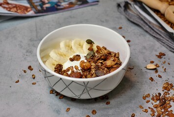Homemade cocoa granola in white bowl with cashew, almond and seeds on wooden background