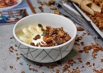 Homemade cocoa granola in white bowl with cashew, almond and seeds on wooden background