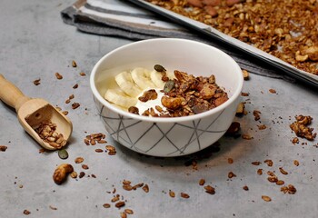 Homemade cocoa granola in white bowl with cashew, almond and seeds on wooden background