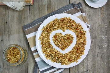Homemade granola in white bowl with almond and seeds on wooden background