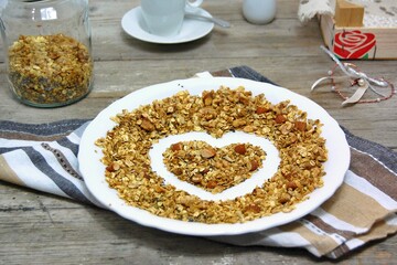 Homemade granola in white bowl with almond and seeds on wooden background