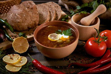 traditional soup solyanka in a brown bowl. soup made from a mixture of different varieties of smoked meat with olives.