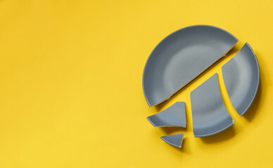Broken gray ceramic plate on yellow background