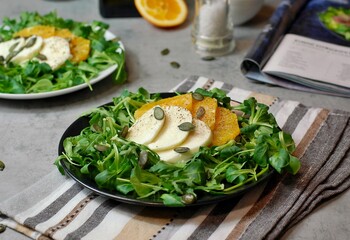 Fresh salad with lettuce, orange, mozzarella and pumpkin seed