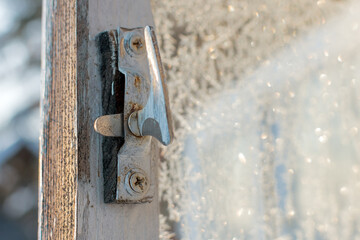 On an open wooden window, an old, obsolete latch. Horizontal photo, soft focus, bokeh.