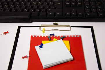 paper clips, red notepad, keyboard lies on a white background