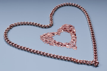 Gold colored chain and a heart-shaped frame made of shiny sequins on a blue background. Festive texture for Valentine's Day, Mother's Day, Women's Day, Wedding Day and Birthday