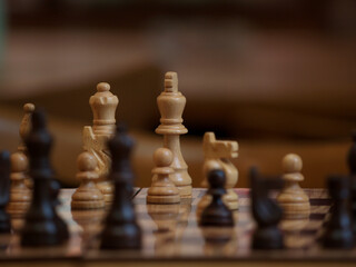 wooden chessboard with the chess queen in focus and a blurred background
